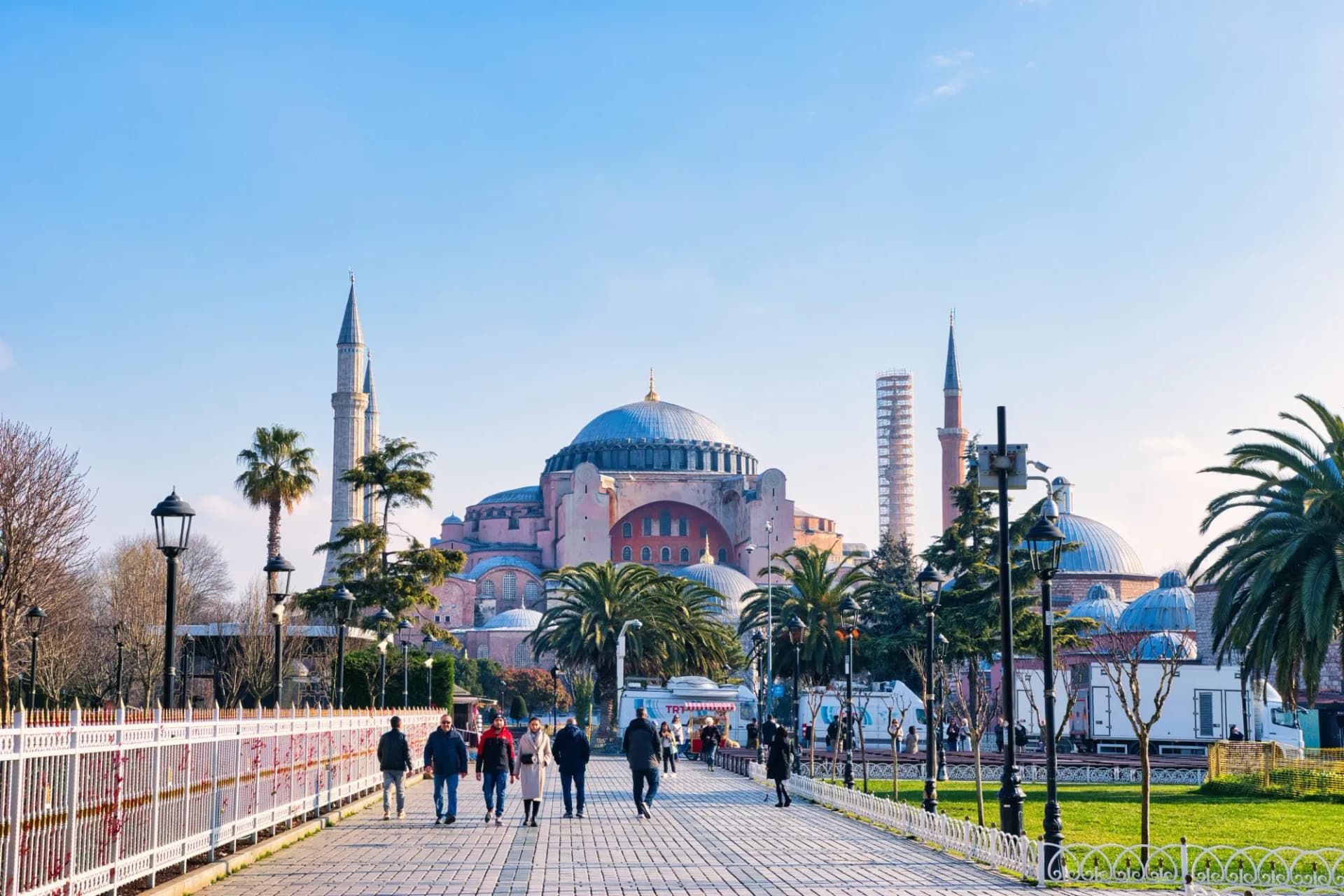 Hagia Sophia Mosque in Istanbul with people walking on a paved path in spring.