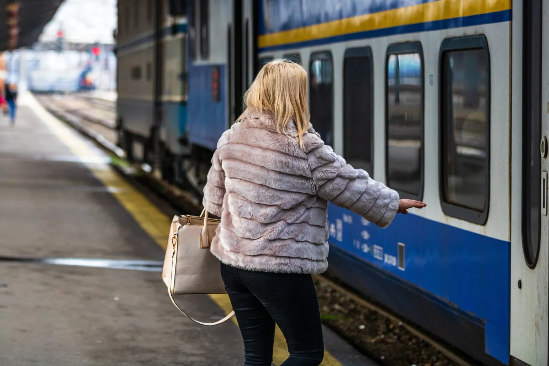 Tourist pulling luggage boards train at railroad station platform in Bucharest, Romania.