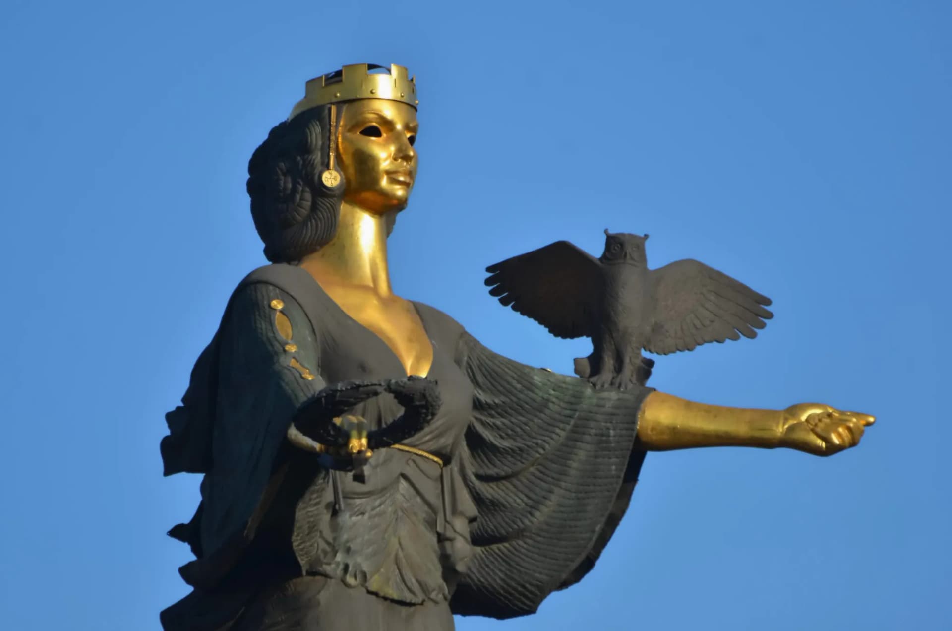 Monument of St. Sofia statue with golden face and owl against clear blue sky in Sofia, Bulgaria.