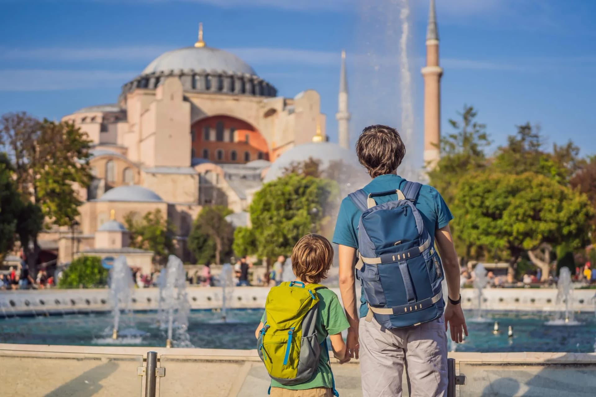 Father and son tourists viewing Hagia Sophia cathedral and minaret over a fountain in Istanbul, Turkey.