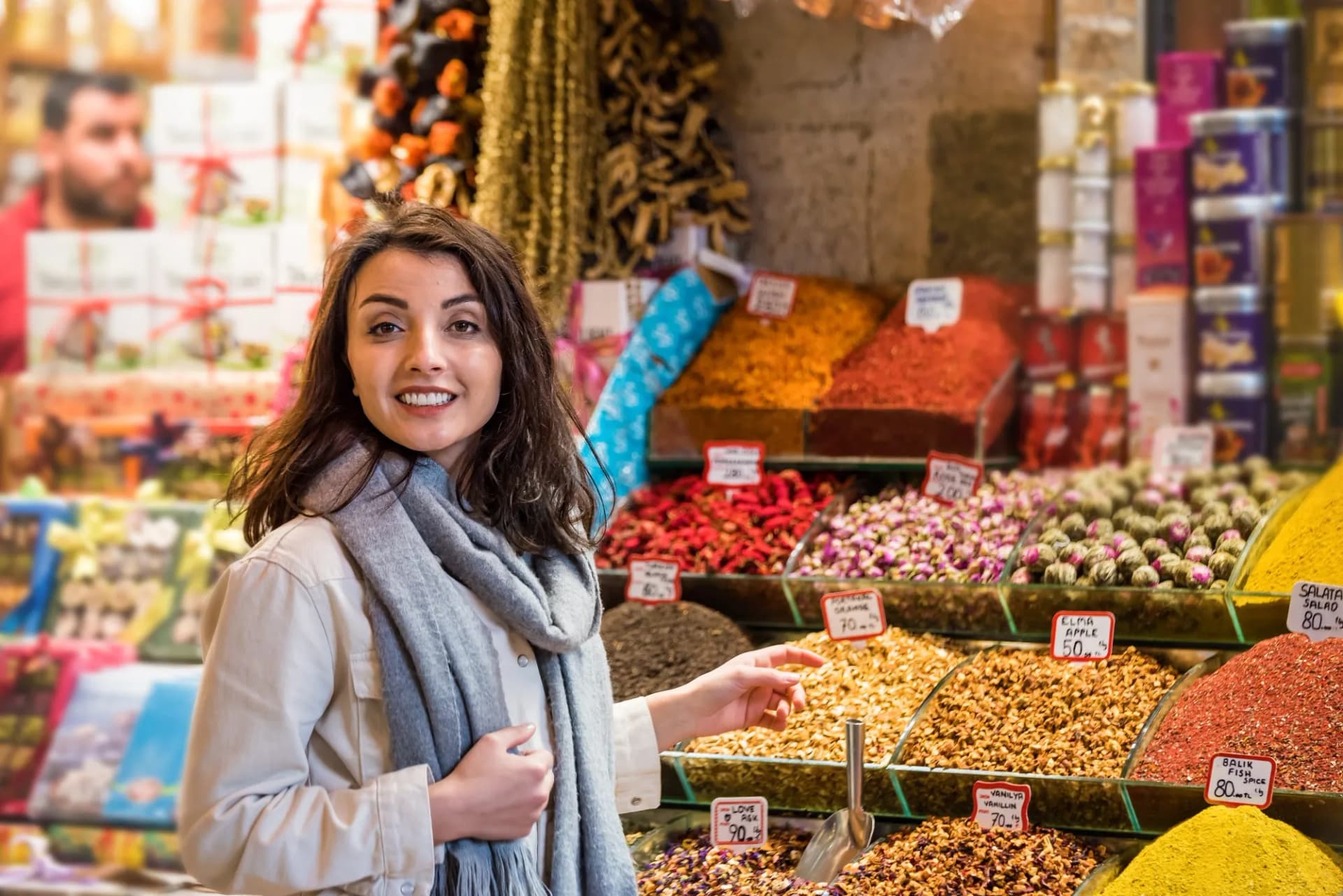 Woman smelling spices at market stall in Egypt bazaar with colorful dried goods.