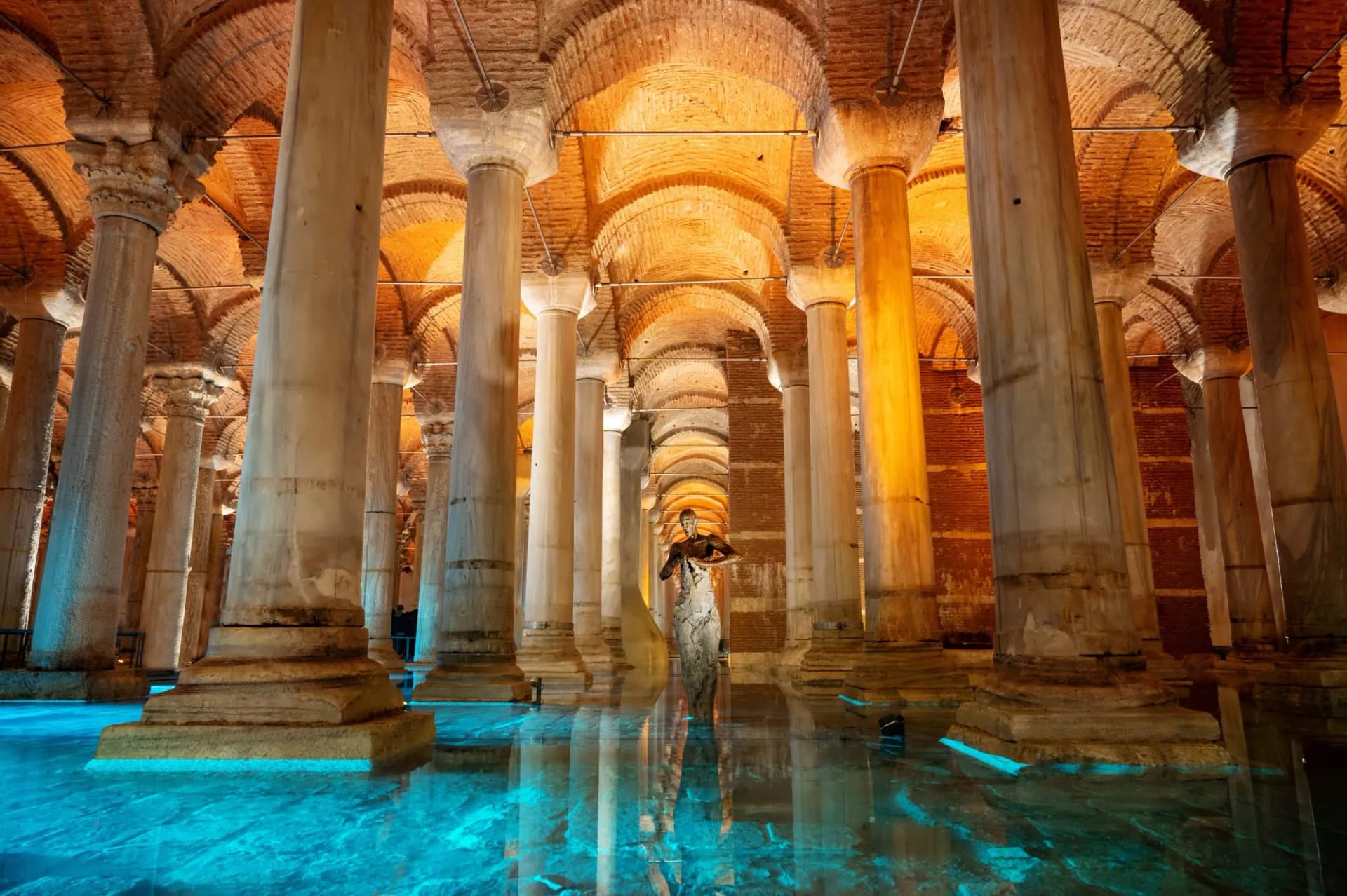 Columns in the Basilica Cistern, Istanbul, reflected in illuminated turquoise water with a statue.