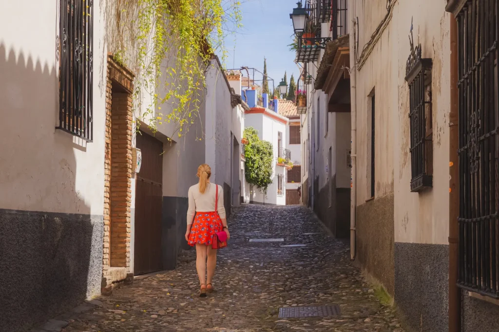 Una giovane turista bionda che esplora le strette stradine acciottolate del centro storico (Albaicin o quartiere arabo) di Granada, in Andalusia, Spagna.