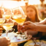 Menschen stoßen mit Wein auf der Sommerterrasse eines Cafés oder Restaurants an