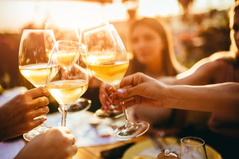 Menschen stoßen mit Wein auf der Sommerterrasse eines Cafés oder Restaurants an