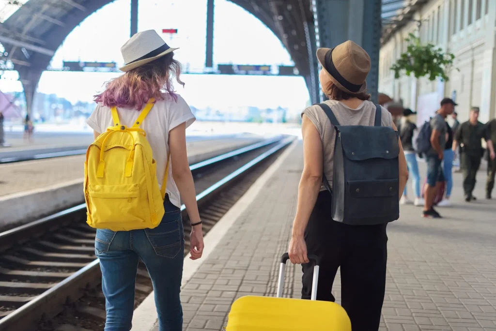 Due donne in viaggio con zaini valigia che camminano lungo la piattaforma