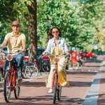 Giovane coppia caucasica felice in bicicletta nelle vecchie strade di Amsterdam